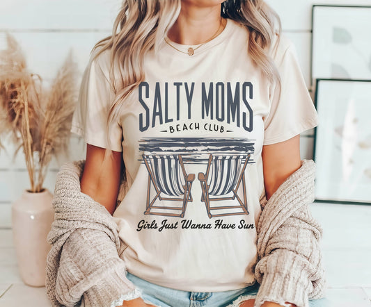 Person wearing a 'Salty Moms Beach Club' t-shirt with lounge chairs graphic.