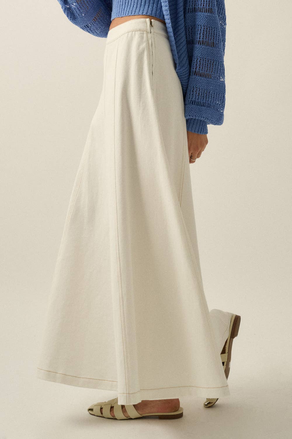Person wearing white wide-leg pants and a blue cardigan on a plain background