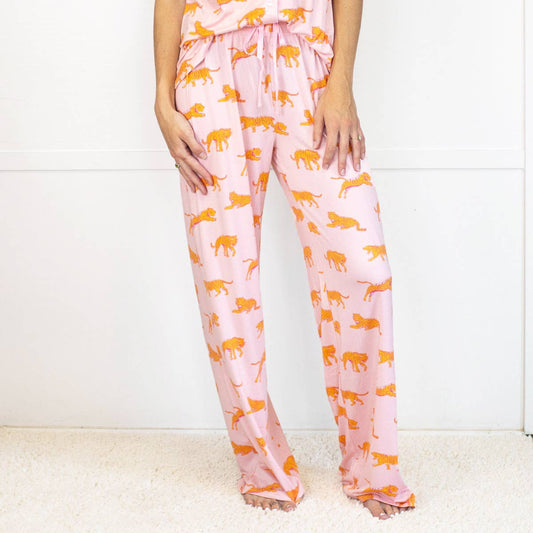 Pink pajama pants with orange panther pattern worn by a person on a white background