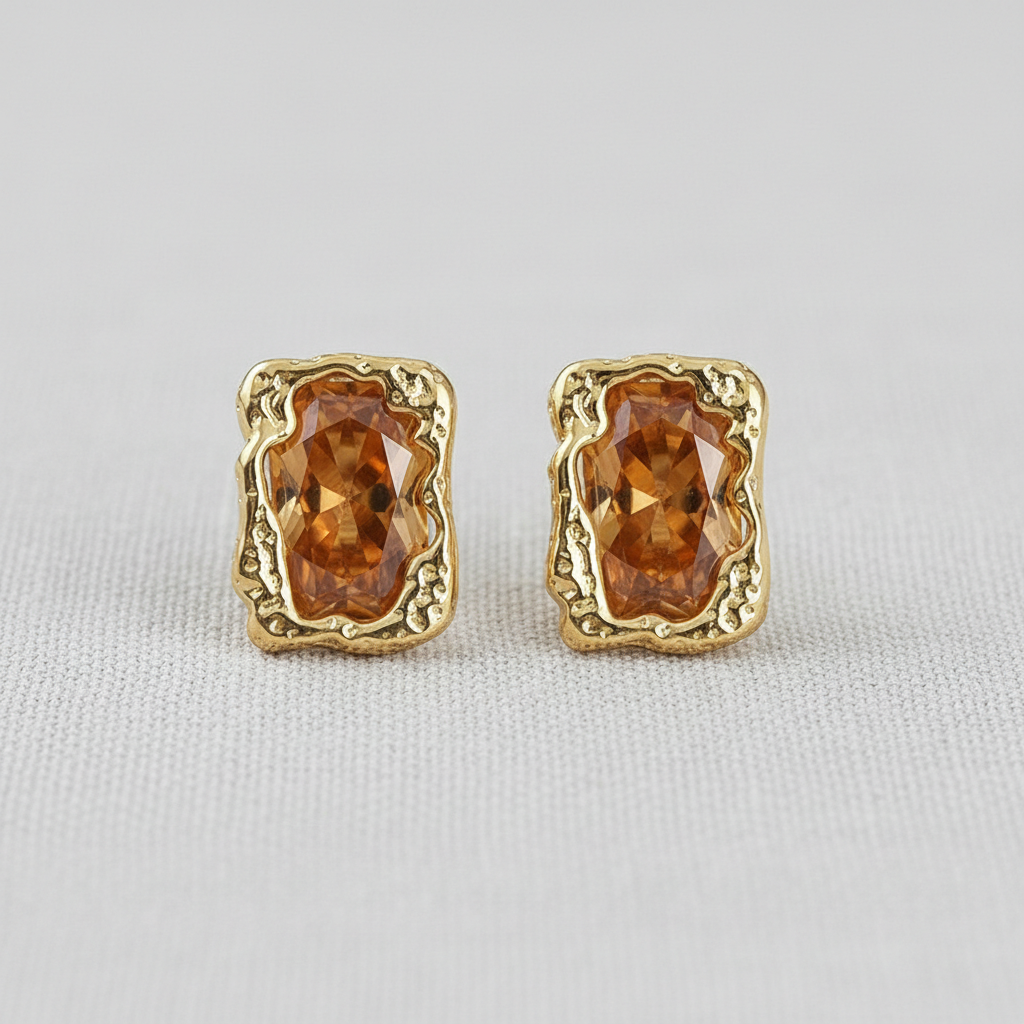 Pair of gold-tone stud earrings with brown faceted stones on white fabric