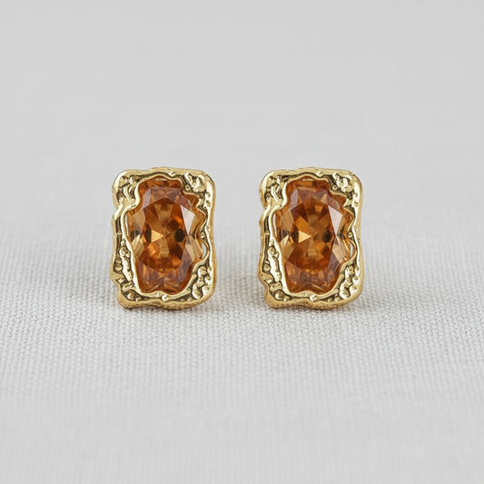 Pair of gold-tone stud earrings with brown faceted stones on white fabric