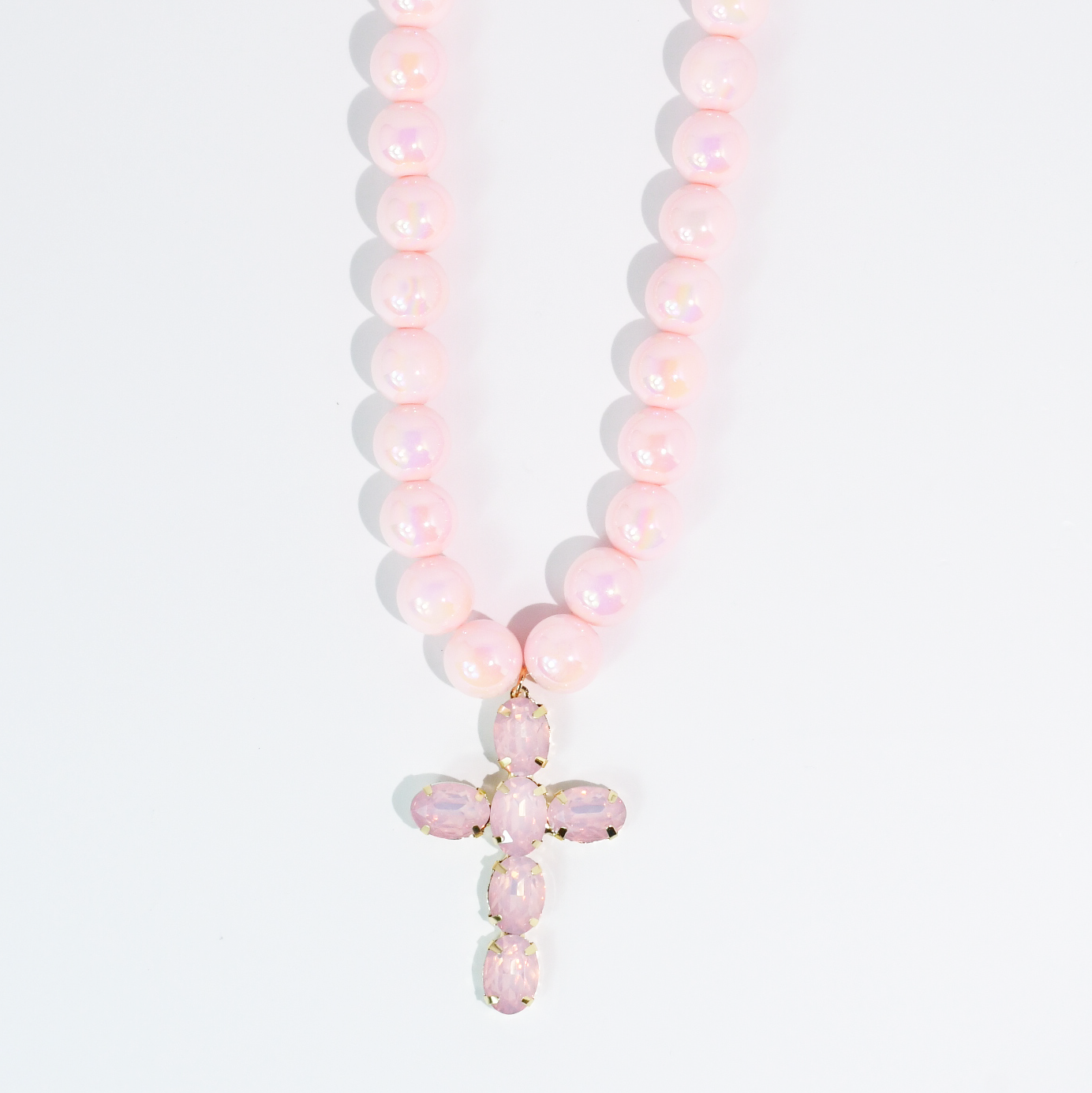 Pink beaded necklace with a faceted crystal cross pendant on a white background