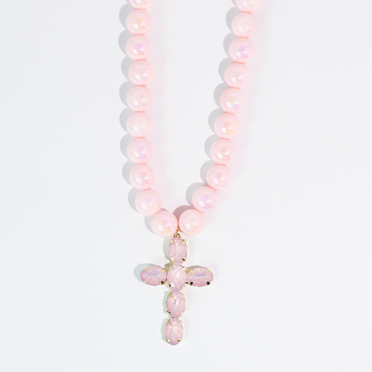 Pink beaded necklace with a faceted crystal cross pendant on a white background