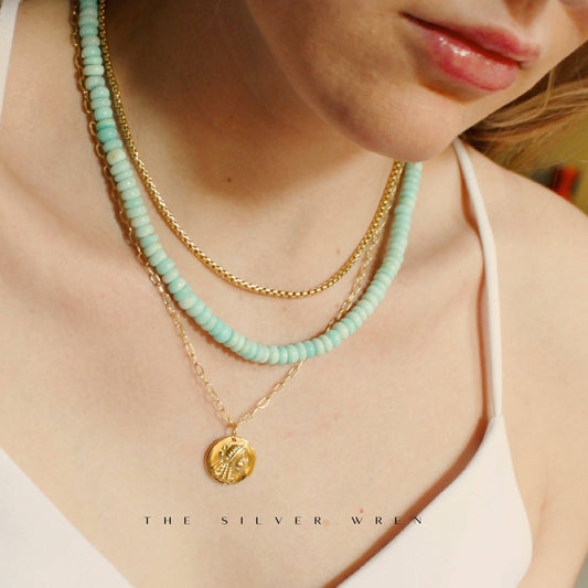 Aqua beaded necklace styled with layered gold chains
