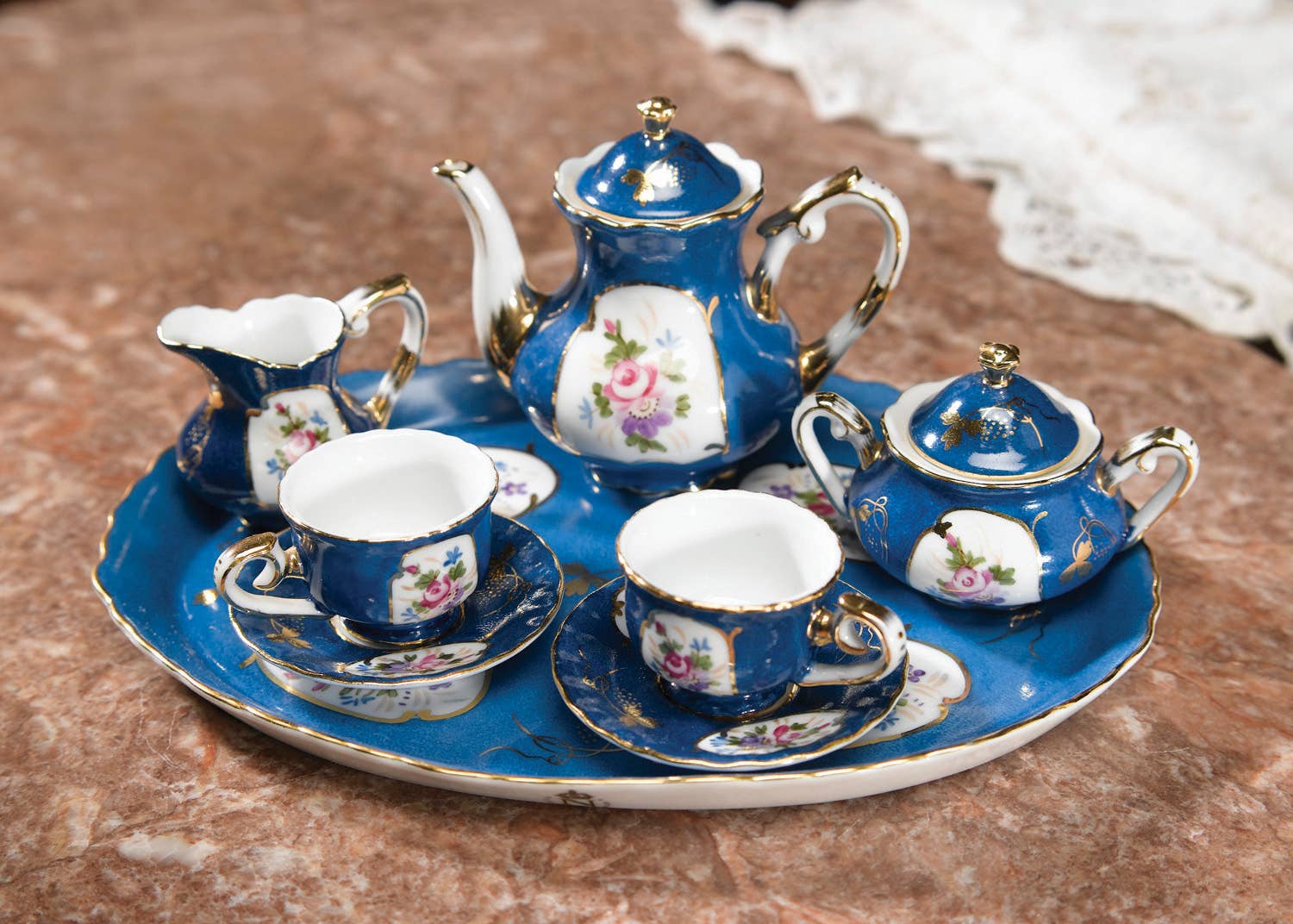 Blue miniature tea set with floral panels and gold trim on a tray