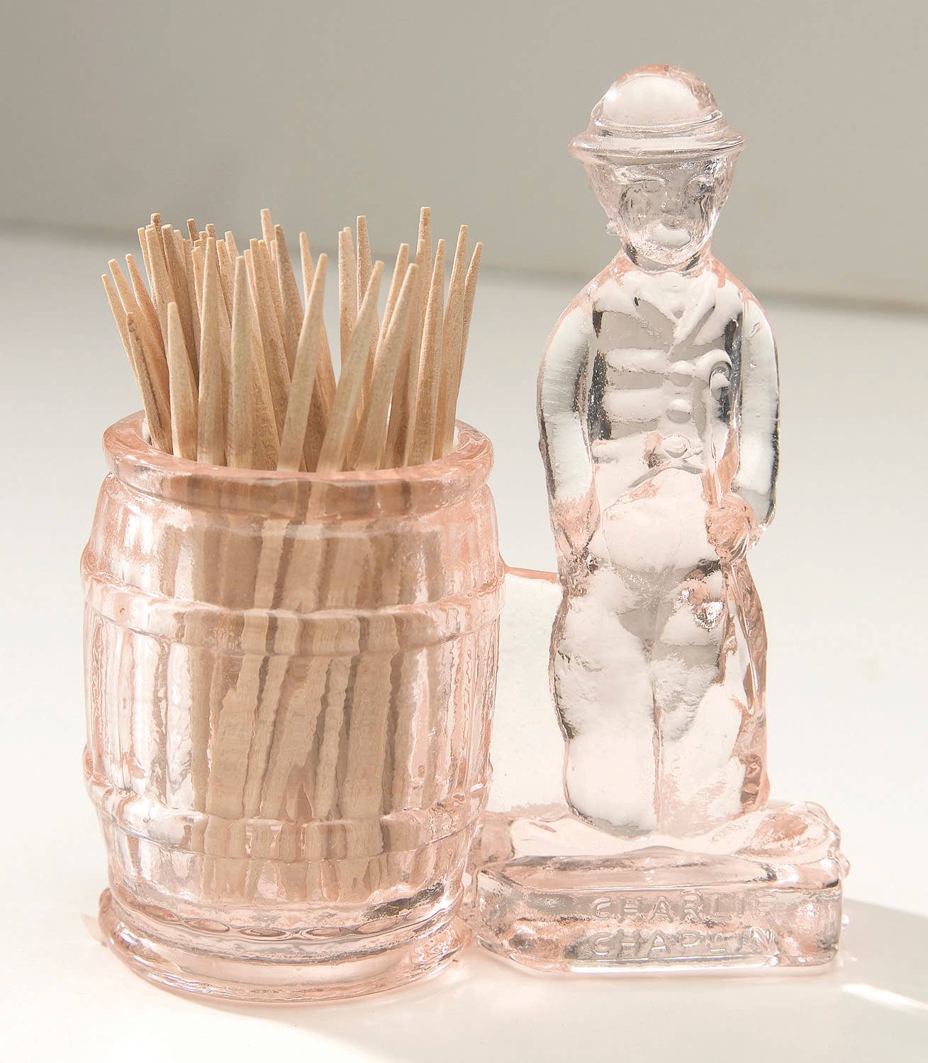Pink glass toothpick holder with barrel cup and standing man figure