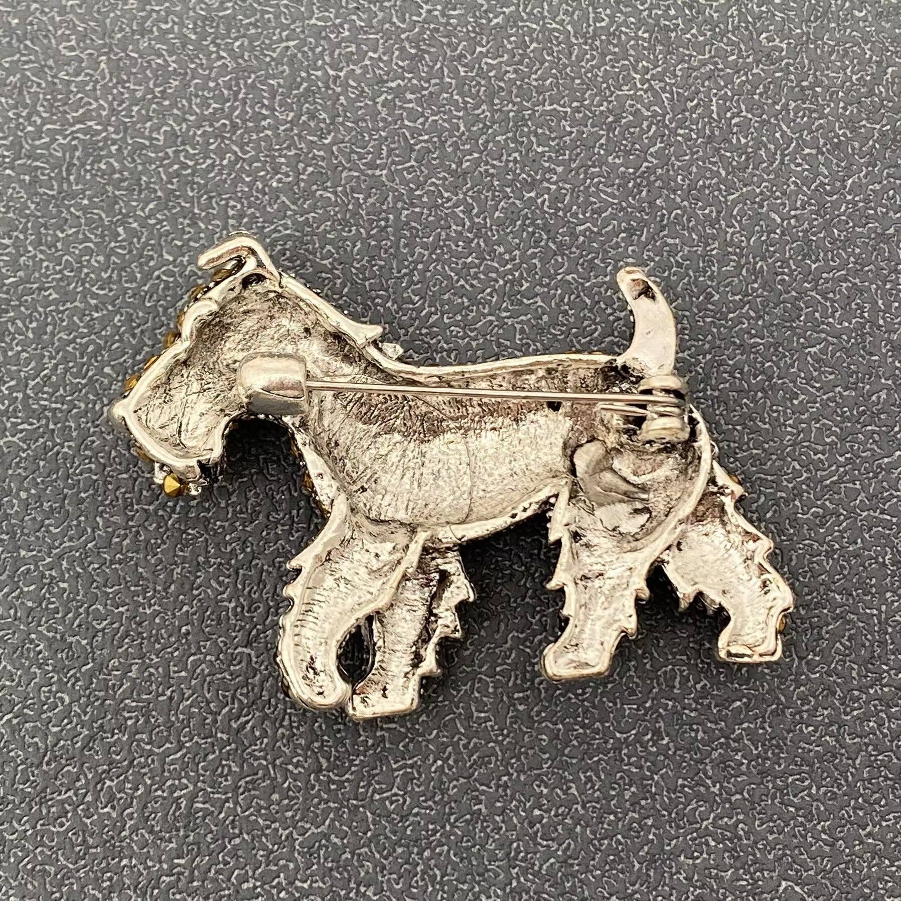 Silver dog-shaped brooch on a textured gray background
