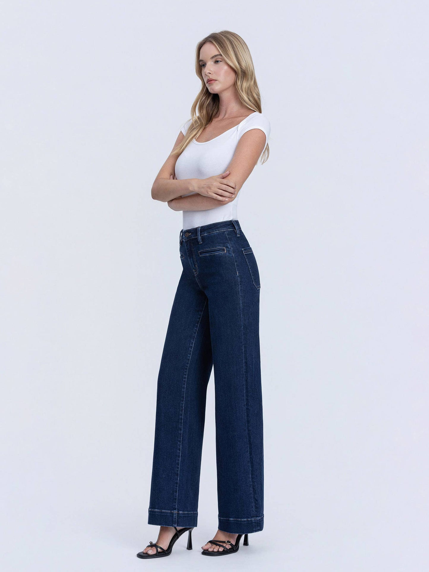 Side pose wearing high rise dark denim wide leg jeans