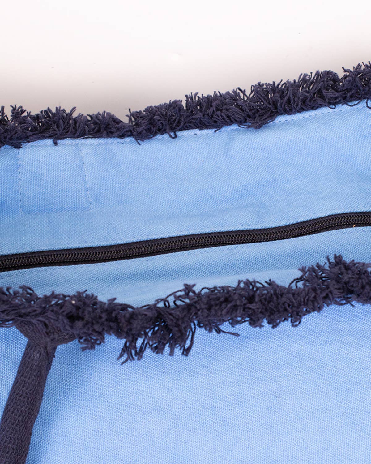 Close-up of blue Dockside tote with navy zipper and fringe trim