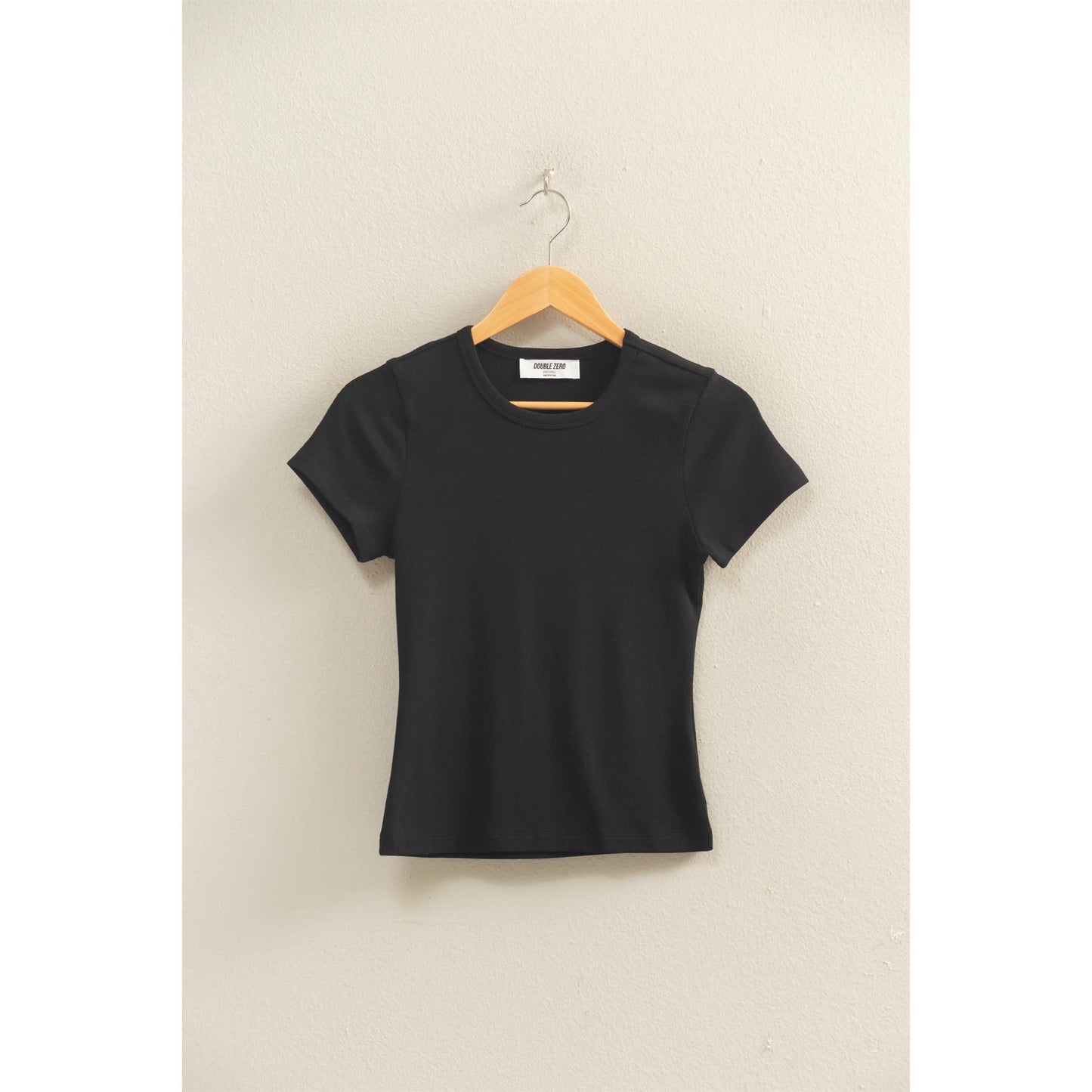 Black crew neck short sleeve top hanging on a wooden hanger