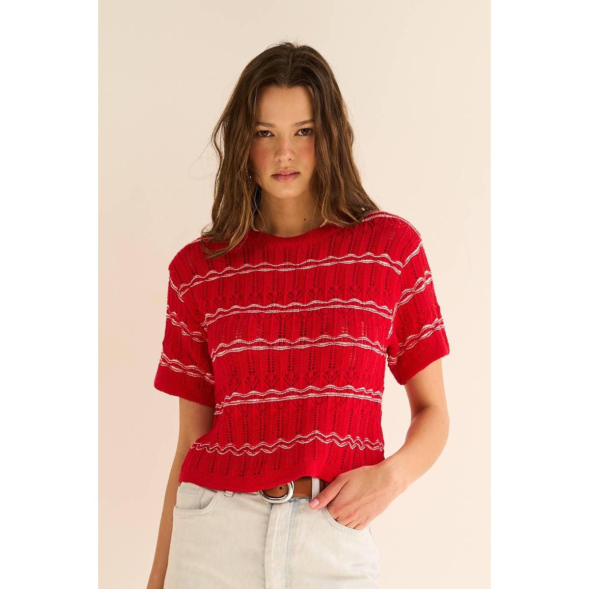 Woman wearing a red and white striped sweater against a beige background