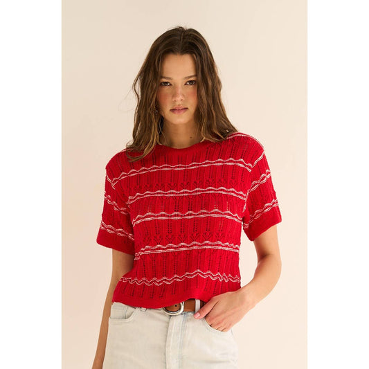 Woman wearing a red and white striped sweater against a beige background