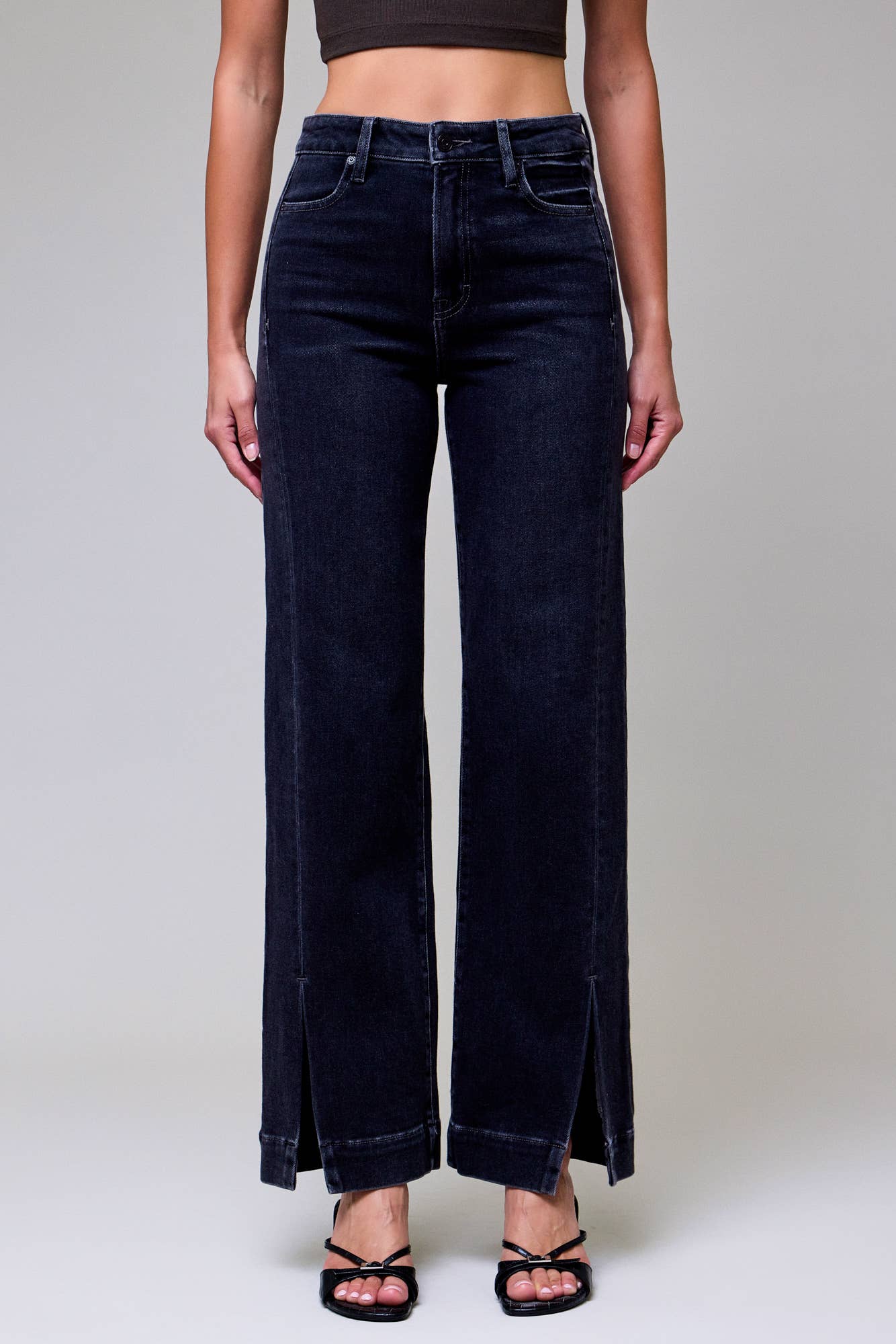 Person wearing dark blue jeans on a plain background