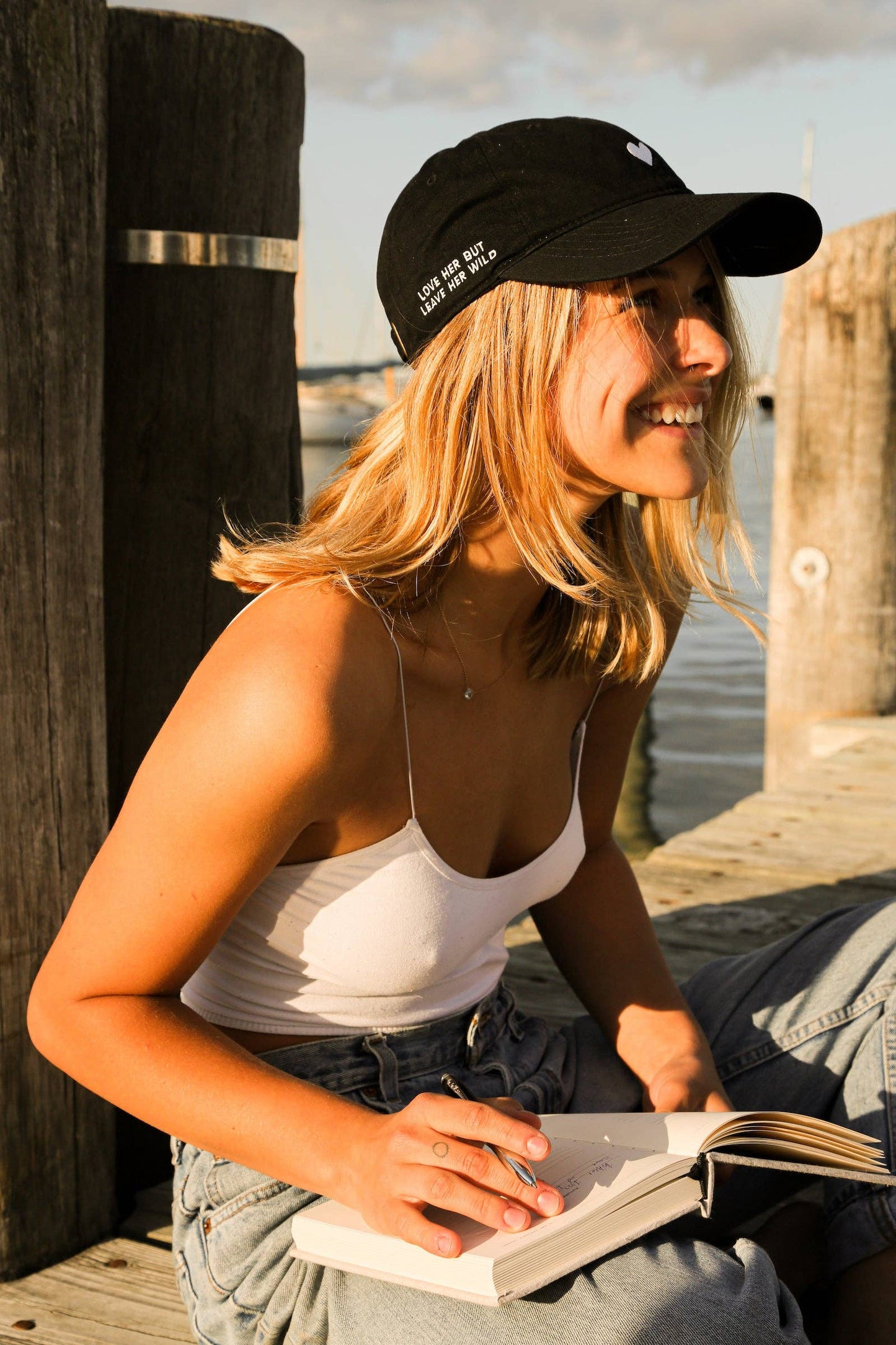 Black dad hat with side slogan worn while writing outdoors