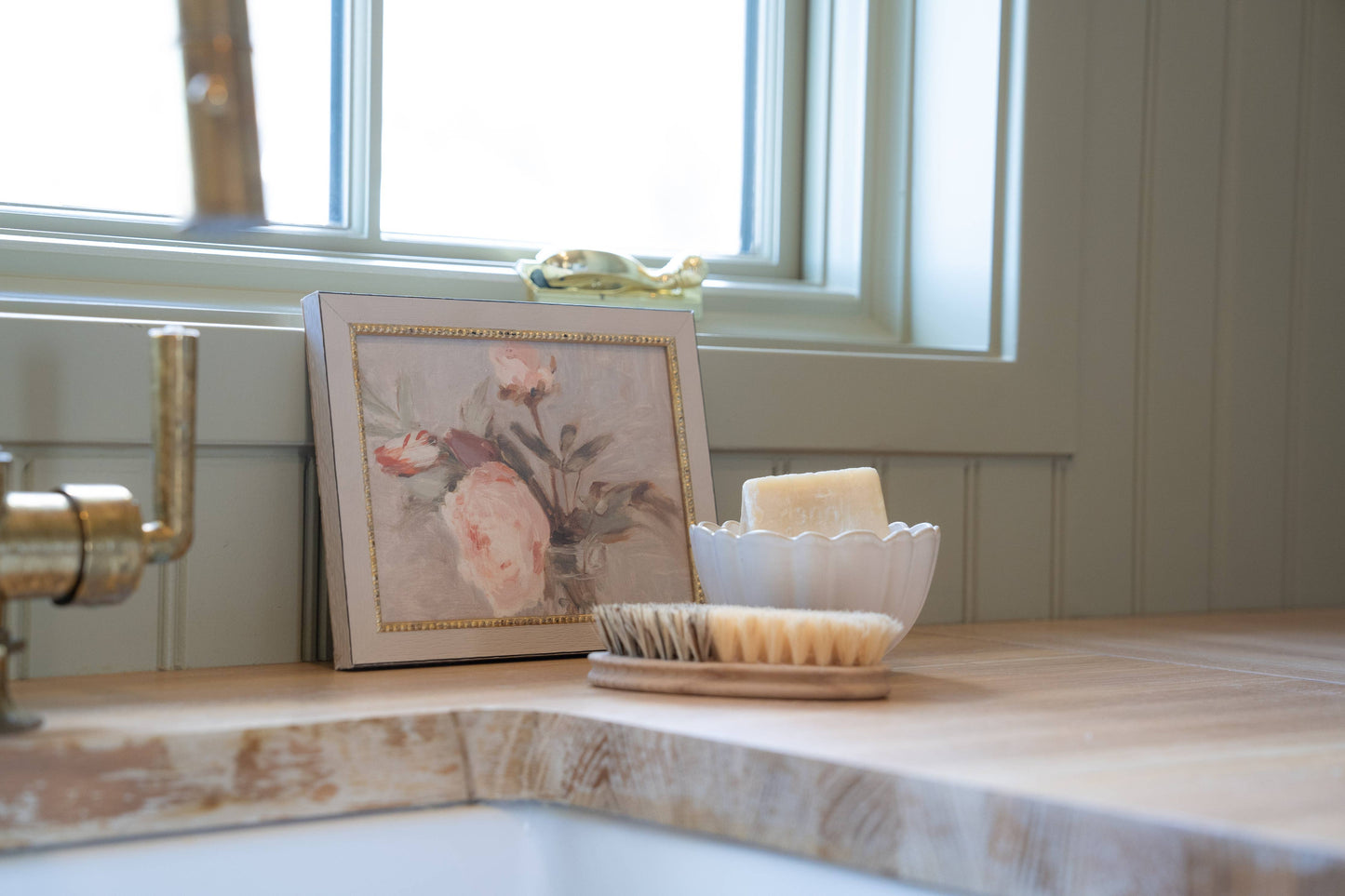 Light pink rose framed canvas print styled on a counter by a window