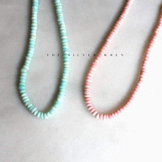 Aqua and pink beaded necklaces on pale stone background