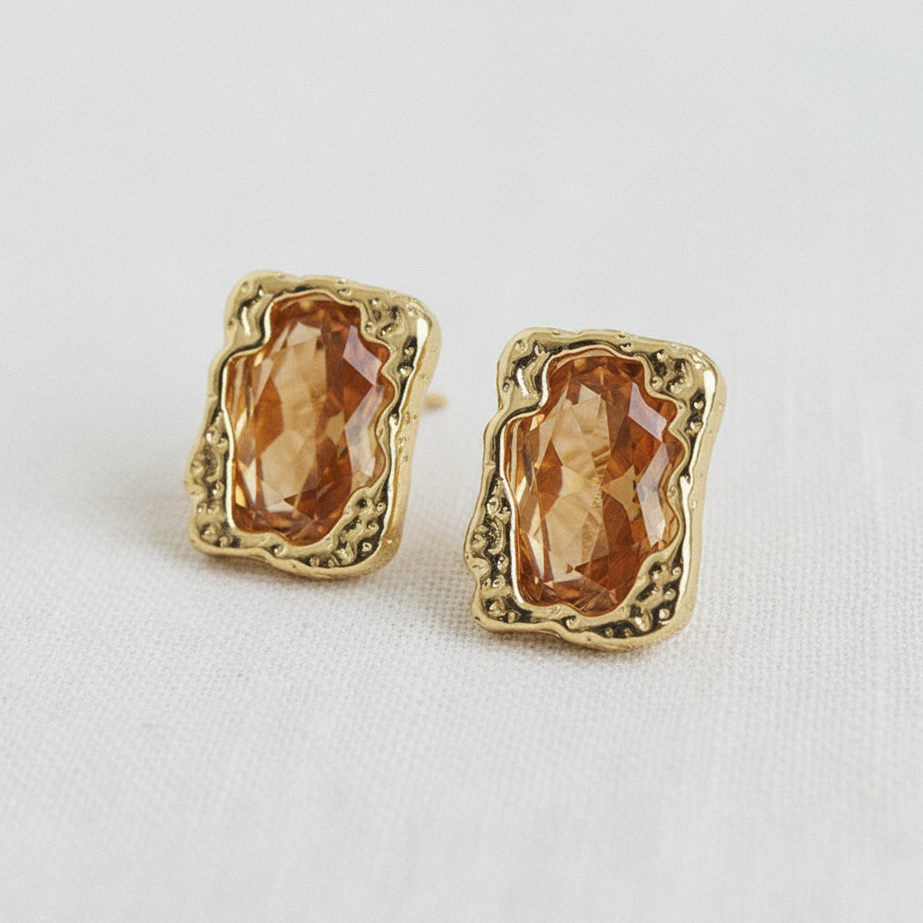 Angled view of brown faceted zircon stud earrings with textured gold-tone frames